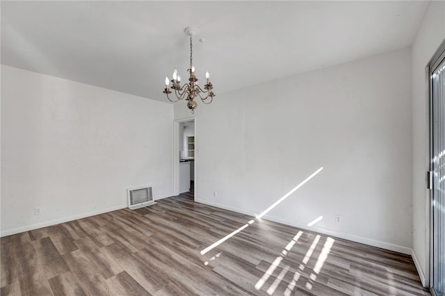 spare room featuring hardwood / wood-style floors and an inviting chandelier