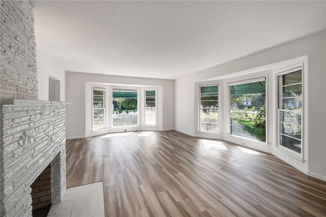 unfurnished living room with light hardwood / wood-style floors and a brick fireplace