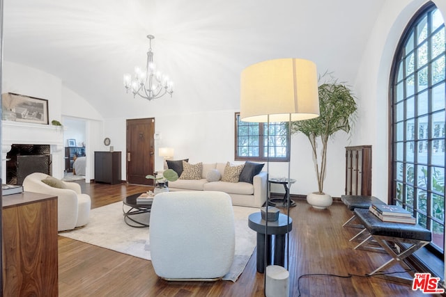 living room featuring hardwood / wood-style flooring, a notable chandelier, and vaulted ceiling