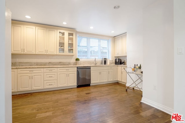 kitchen featuring stainless steel dishwasher, light hardwood / wood-style floors, and light stone countertops