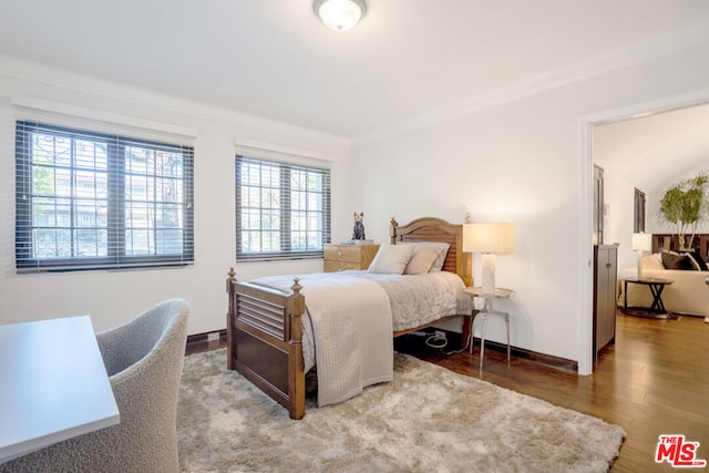 bedroom featuring hardwood / wood-style floors, vaulted ceiling, and ornamental molding