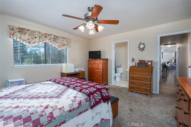 bedroom with connected bathroom, a textured ceiling, light colored carpet, and ceiling fan