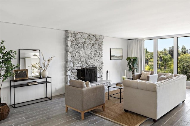 living room with dark wood-type flooring and a stone fireplace