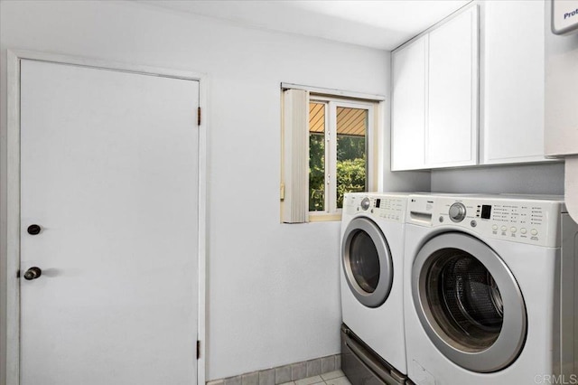 laundry room with washing machine and dryer, light tile patterned floors, and cabinets