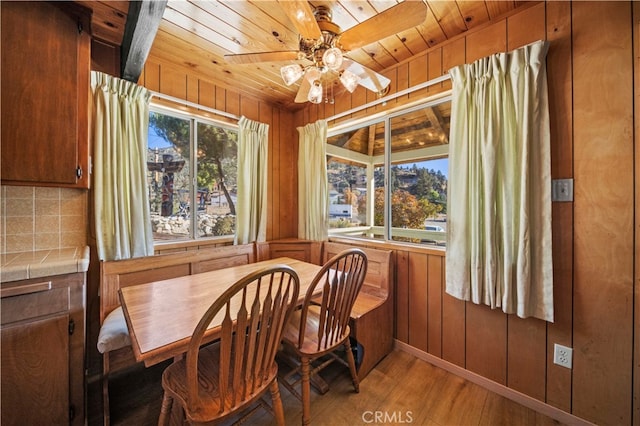 dining room with ceiling fan, wood walls, wood-type flooring, and wood ceiling