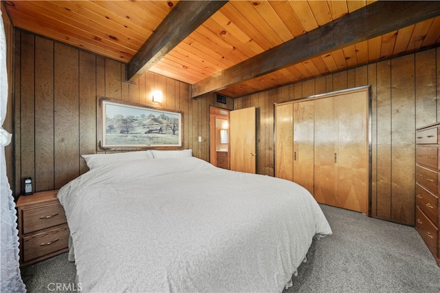 bedroom with a closet, beamed ceiling, wooden walls, wooden ceiling, and carpet floors