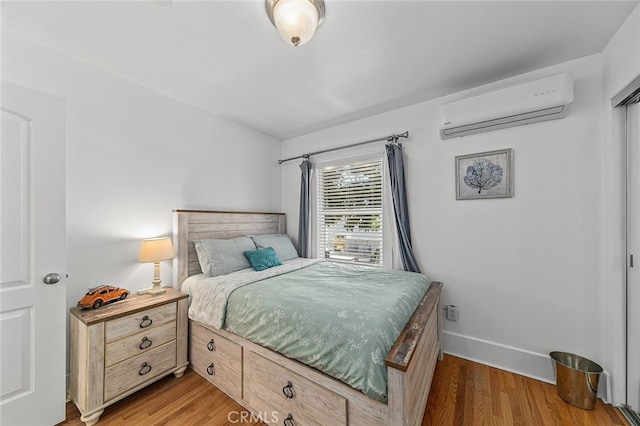 bedroom with a wall mounted AC and wood-type flooring