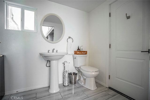 bathroom featuring toilet, sink, and wood-type flooring