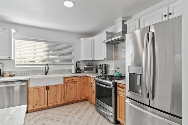 kitchen featuring wall chimney exhaust hood, sink, white cabinetry, and stainless steel appliances