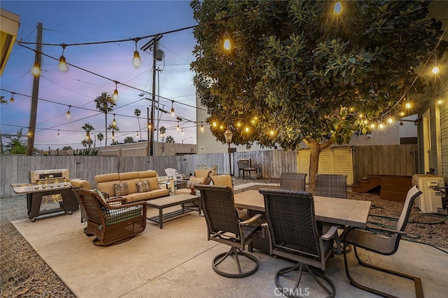 patio terrace at dusk with an outdoor hangout area and area for grilling