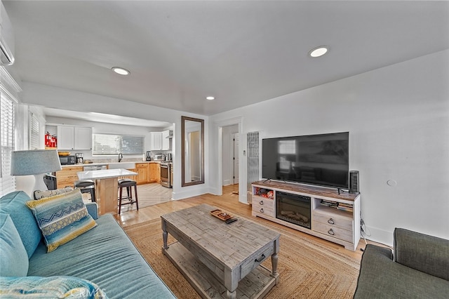 living room with a wall mounted air conditioner and light wood-type flooring