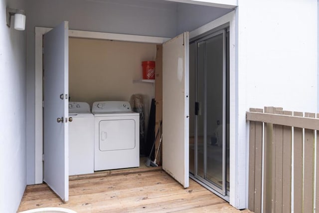 clothes washing area with washer and clothes dryer and light wood-type flooring