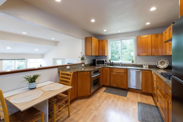 kitchen with a healthy amount of sunlight, lofted ceiling, appliances with stainless steel finishes, and dark stone counters