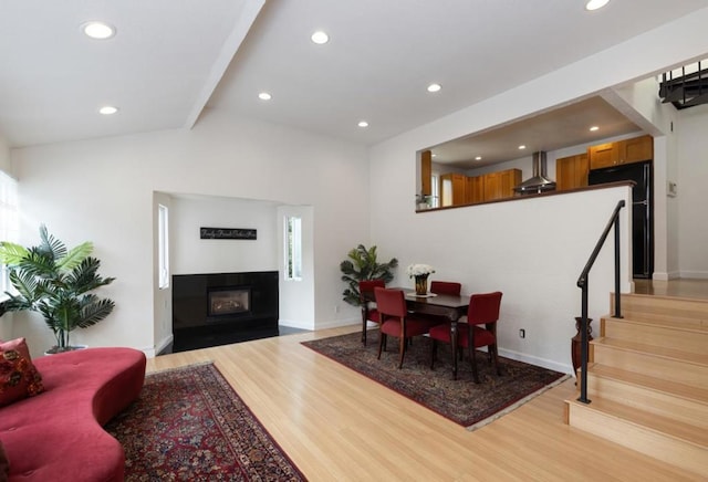 dining room with lofted ceiling with beams and light hardwood / wood-style flooring