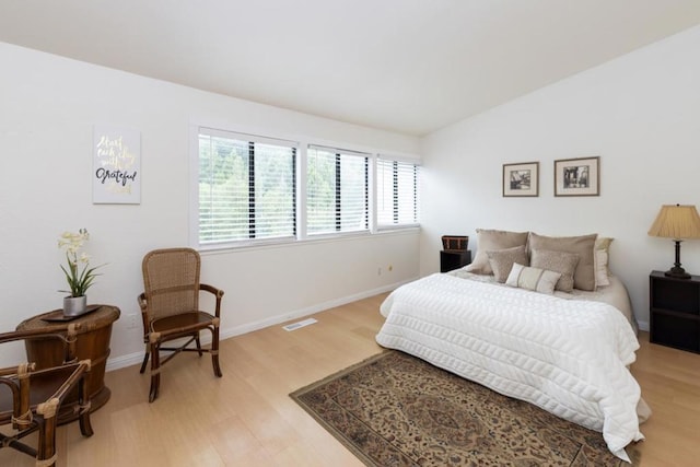 bedroom featuring light hardwood / wood-style floors and lofted ceiling