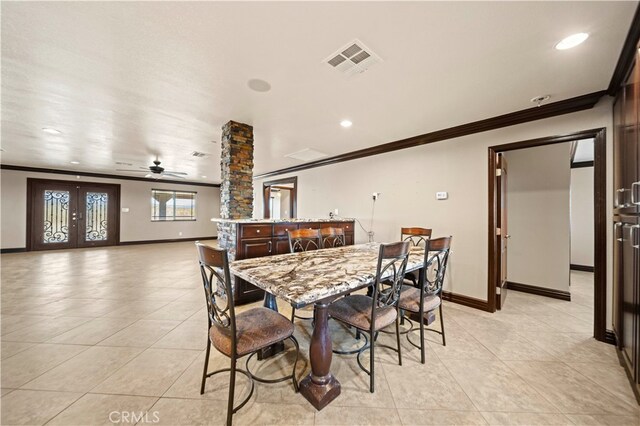 dining space with ceiling fan, light tile patterned floors, ornamental molding, ornate columns, and french doors