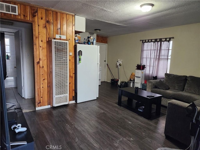 living room featuring a textured ceiling, a wealth of natural light, dark hardwood / wood-style flooring, and wood walls