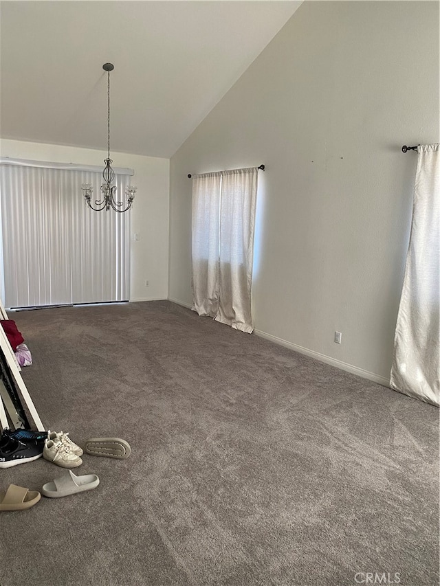 carpeted spare room with a notable chandelier and vaulted ceiling