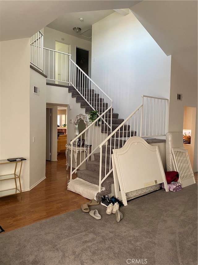 stairway with hardwood / wood-style flooring and a towering ceiling