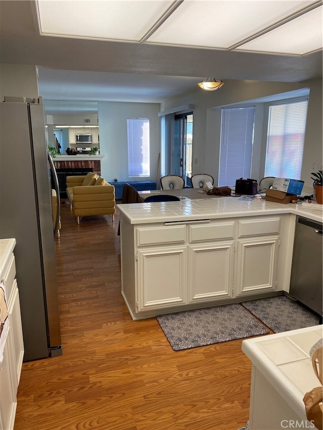 kitchen featuring kitchen peninsula, appliances with stainless steel finishes, a wealth of natural light, and light wood-type flooring