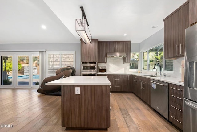 kitchen with light hardwood / wood-style floors, a kitchen island, extractor fan, and appliances with stainless steel finishes