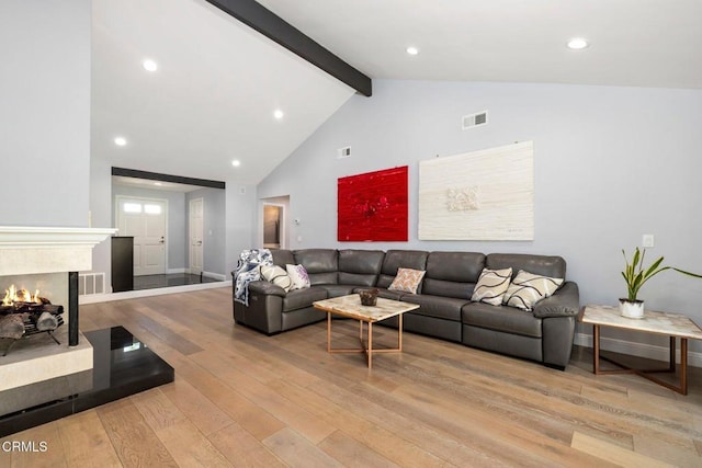 living room with beam ceiling, light wood-type flooring, and high vaulted ceiling