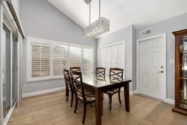 dining room featuring a chandelier, vaulted ceiling, and light hardwood / wood-style flooring