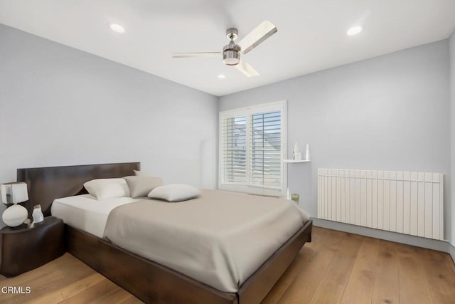 bedroom featuring radiator heating unit, light wood-type flooring, and ceiling fan