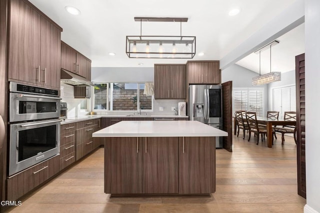 kitchen with appliances with stainless steel finishes, light hardwood / wood-style floors, plenty of natural light, and hanging light fixtures