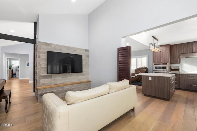 living room with light hardwood / wood-style floors and high vaulted ceiling