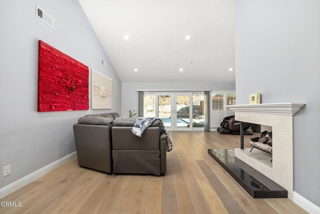 living room with french doors, light wood-type flooring, and high vaulted ceiling