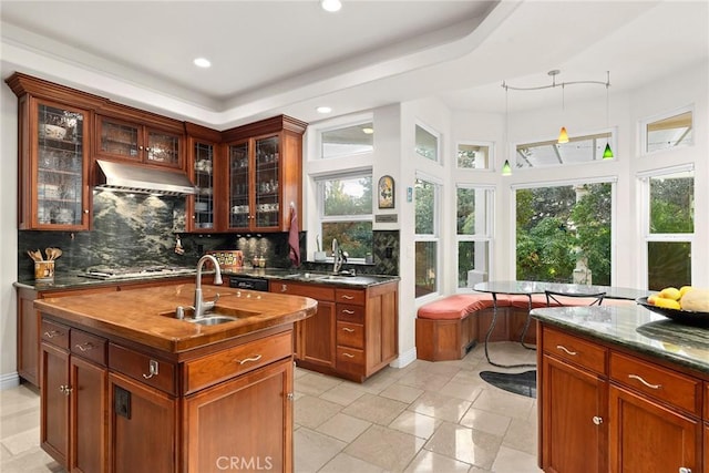 kitchen featuring sink, a center island with sink, stainless steel gas cooktop, and tasteful backsplash