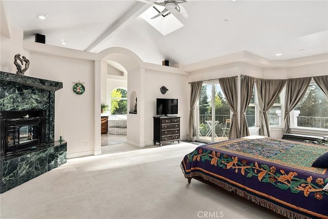 carpeted bedroom with ensuite bathroom, a skylight, ceiling fan, access to outside, and high vaulted ceiling