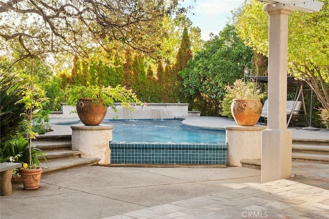 view of pool featuring pool water feature and a patio