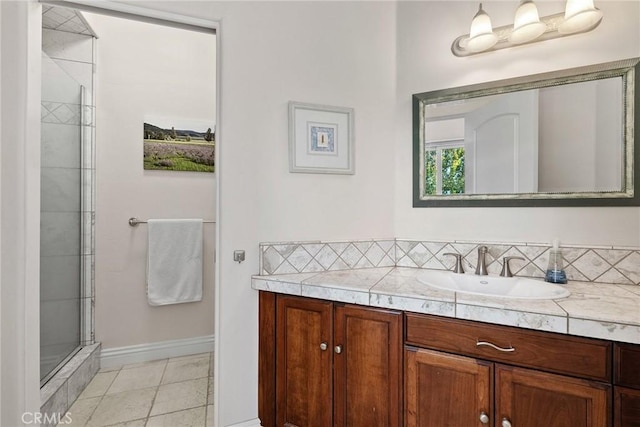 bathroom with tile patterned floors, walk in shower, vanity, and tasteful backsplash