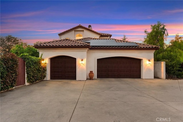 mediterranean / spanish home with a garage and solar panels