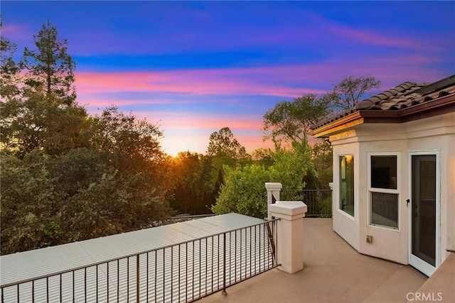 patio terrace at dusk featuring a balcony