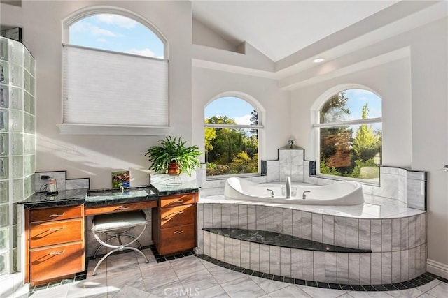 bathroom featuring tiled tub and vaulted ceiling