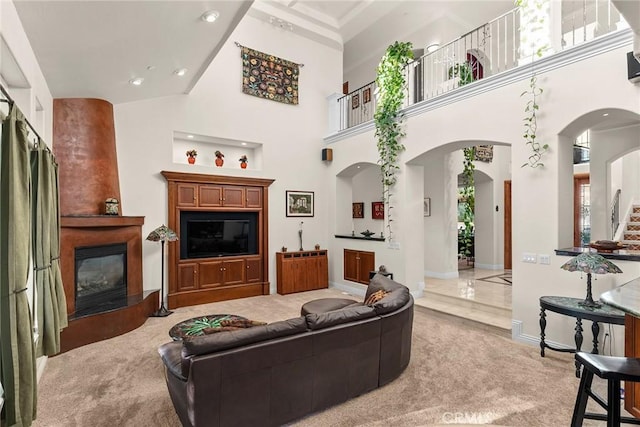 carpeted living room with a fireplace and a towering ceiling