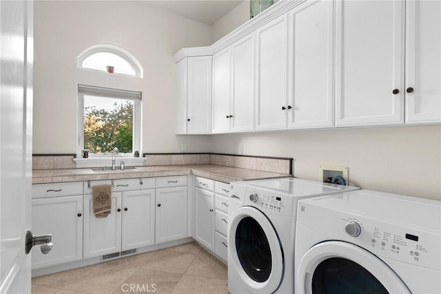 laundry area with cabinets, light tile patterned floors, sink, and washing machine and dryer