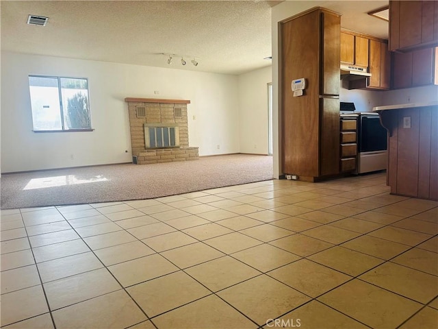 kitchen with range, a textured ceiling, light colored carpet, and a brick fireplace