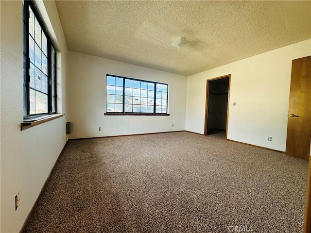 unfurnished bedroom with carpet, a textured ceiling, and multiple windows