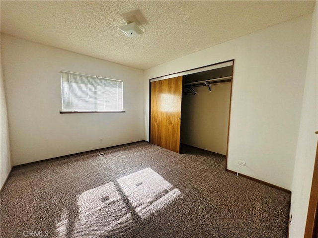 unfurnished bedroom with a closet, dark carpet, and a textured ceiling