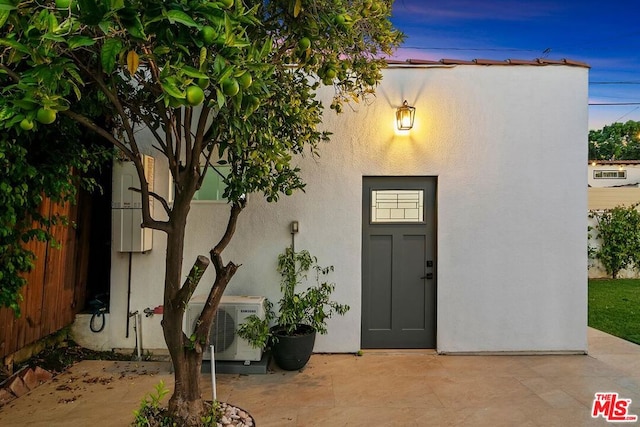 exterior entry at dusk with ac unit and a patio