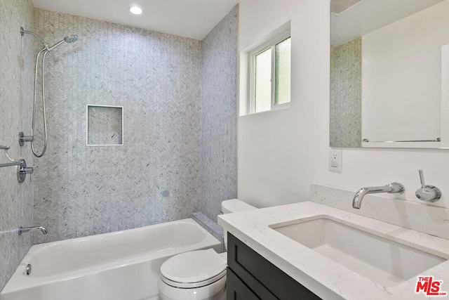 full bathroom featuring vanity, tiled shower / bath combo, and toilet