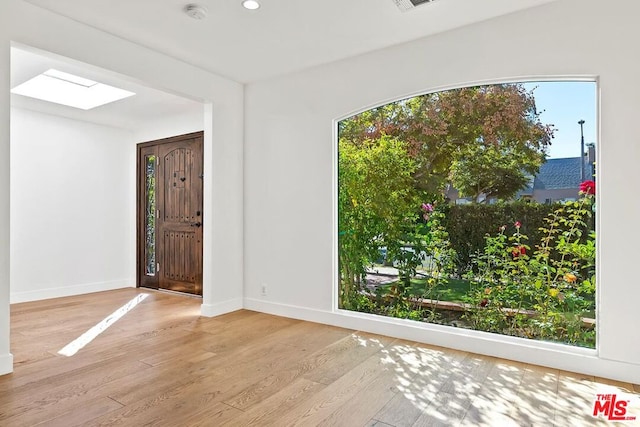 foyer entrance with a skylight and light wood-type flooring