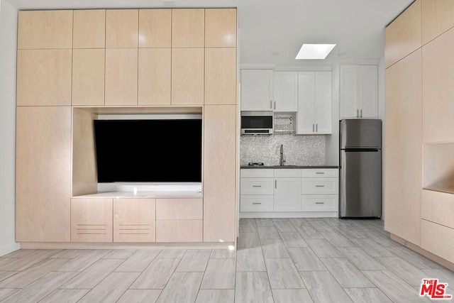 kitchen featuring appliances with stainless steel finishes, light hardwood / wood-style flooring, and white cabinetry