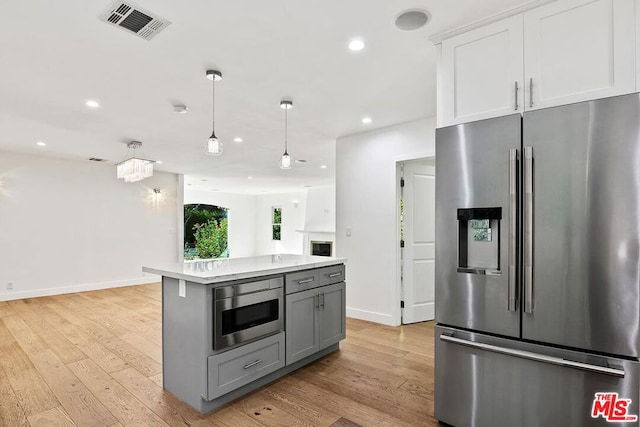 kitchen featuring a kitchen island, light wood-type flooring, white cabinetry, and appliances with stainless steel finishes