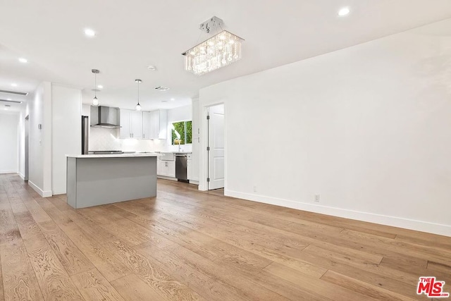 kitchen featuring wall chimney exhaust hood, light hardwood / wood-style flooring, a kitchen island, and pendant lighting