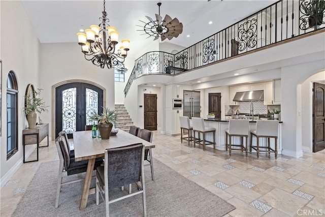 dining area featuring a towering ceiling, a notable chandelier, and french doors